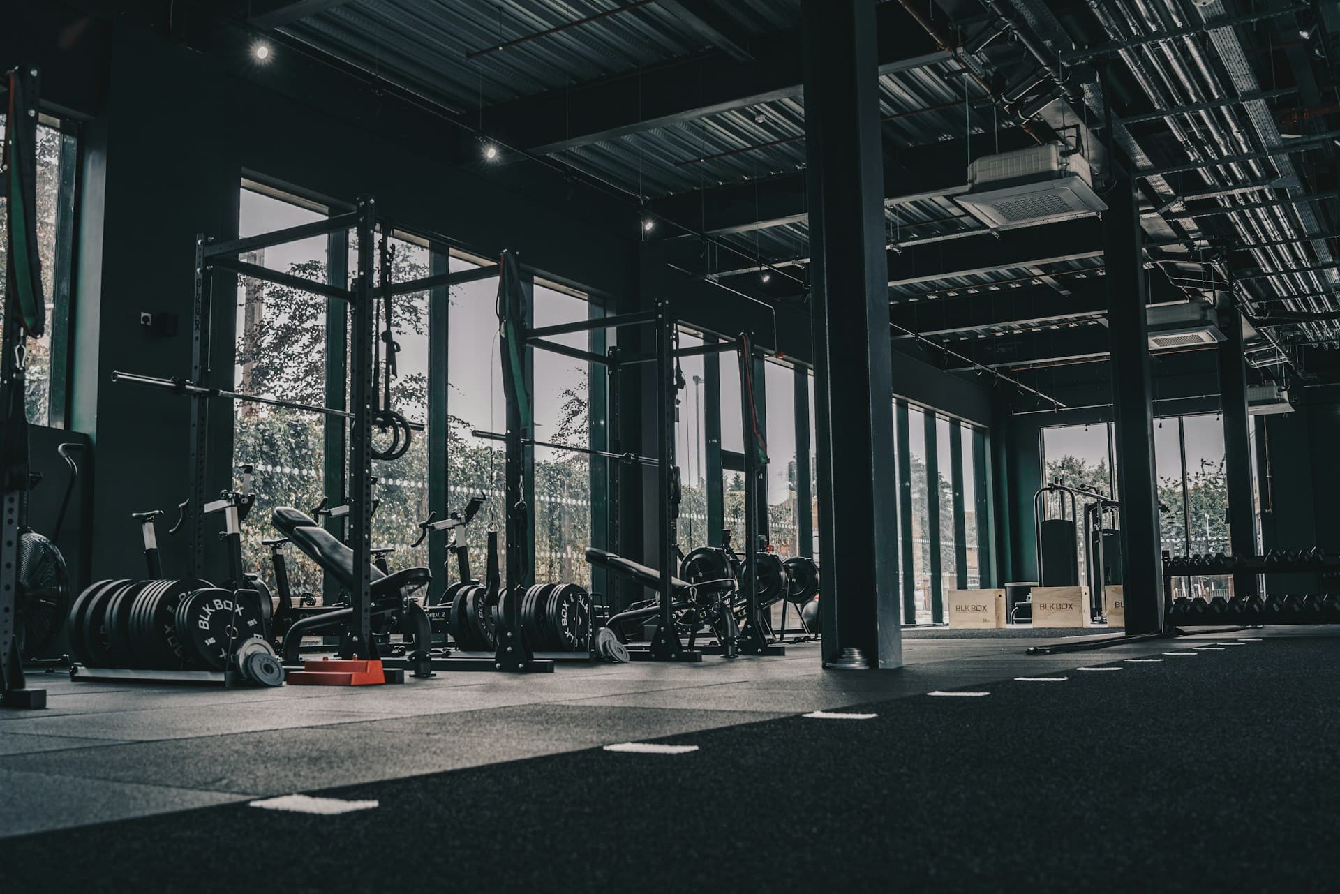 Boutique gym floor with weight racks, benches, and tall windows
